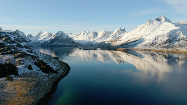 Aerial view of a mirroring Lofoten fjord with frozen mountains in the background - rising, drone shot