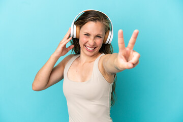 Fototapeta premium Young caucasian woman isolated on blue background listening music and singing