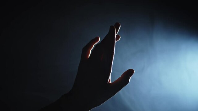 female hand reaching towards a heavy light source, closeup
