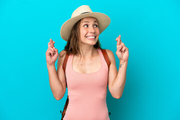 Young caucasian woman in summer holidays isolated on blue background with fingers crossing