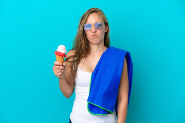 Naklejka premium Young caucasian woman holding ice cream and wearing a beach towel isolated on blue background with sad expression