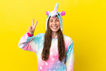 Girl with unicorn pajamas over isolated background smiling and showing victory sign © luismolinero