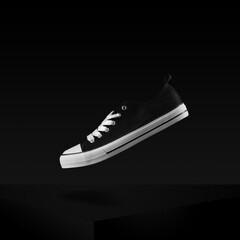 Black sneakers classic vintage shoe levitating in air stylish and fashion shot . Shoes on dark background with copy space