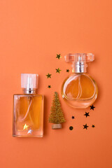 Different Perfume Bottles with Golden Christmas Tree and Golden Confetti on Orange Background Holiday Christmas Gift Concept Vertical Minimal