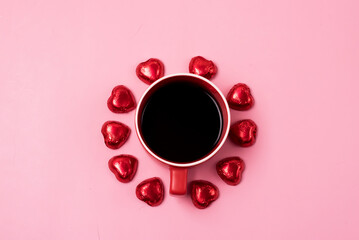 Red Cup of Coffee and Chocolate Candy Heart Shaped Around Cup on Pink Background Top View St Valentine Love Holiday Background