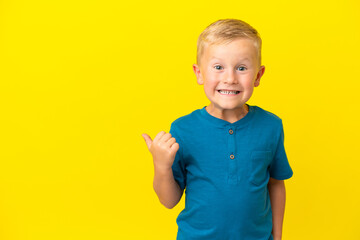 Little Russian boy isolated on yellow background pointing to the side to present a product
