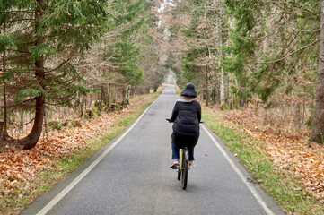 Girl on bicycle rides in autumn foggy park