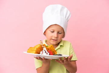 Little Russian boy holding waffles over isolated background