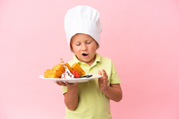Little Russian boy holding waffles over isolated background