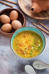 Turquoise bowl of chinese traditional tomato egg-drop soup, vertical shot over roseate metal background, elevated view