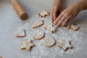 kids Little hands with handmade cookie on wooden table. Christmas gingerbreads, different shapes.