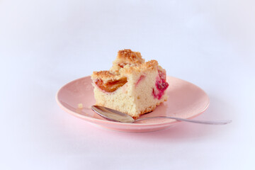 A piece of homemade plum cake on a pink plate. White background, easy to isolated.