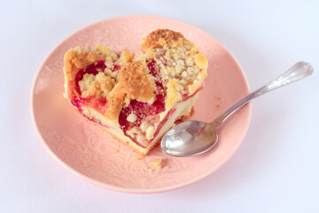 A piece of home-made plum cake in the shape of a heart, on a pink plate. White background, easy to isolate.