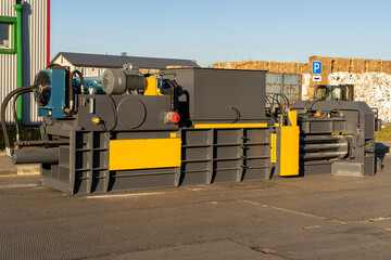 Photo of equipment for recycling pressed waste paper at a landfill with garbage on the street