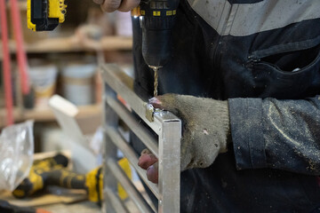 Photo of a male hand that drills metalwork in a workshop