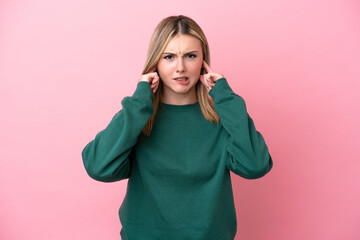 Young caucasian woman isolated on pink background frustrated and covering ears