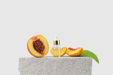 Peach essential oil in a transparent bottle with a dropper and fresh peaches on a natural stone podium