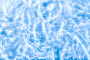 Blurred blue clear calm water surface texture with splashes and bubbles. abstract nature background. Water waves.