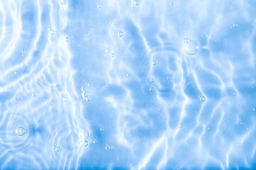 Blurred blue clear calm water surface texture with splashes and bubbles. abstract nature background. Water waves.