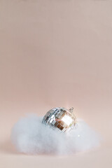 disco ball in an imitated cloud, pink background, empty space for text