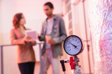 selective focus of manometer of data center cooling system near blurred interracial engineers