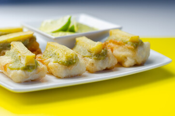 Skinless and boneless battered Alaska Pollock fillet pieces, topped with mushy peas and fried potato