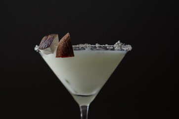 Coconut cocktail in martini glass based on the rum decorated with coconut flakes and coconut pieces
