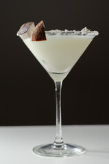 Coconut cocktail in martini glass based on the rum decorated with coconut flakes and coconut pieces