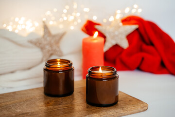 burning natural soy scented candle on the background of Christmas decorations.