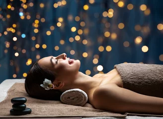 Foto auf Acrylglas Spa Wellness-, Beauty- und Entspannungskonzept - junge Frau liegt im Spa oder Massagesalon über goldenen Lichtern auf blauem Hintergrund