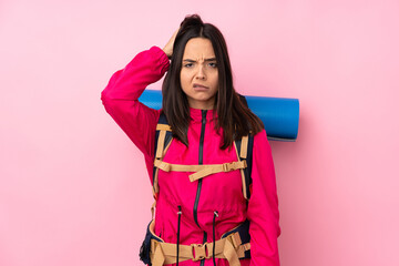 Young mountaineer girl with a big backpack over isolated pink background with an expression of frustration and not understanding