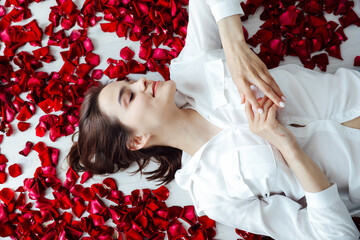 beautiful woman lies in the petals of a red rose