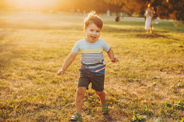 Caucasian boy runs along the field on camera. Childhood. Front view. Sunset.