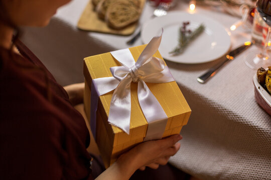 winter holidays and celebration concept - close up of happy woman opening christmas gifts at home dinner party