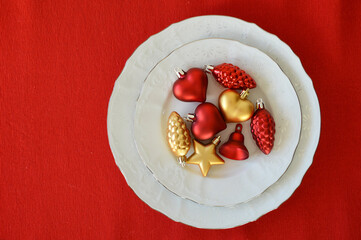 Christmas table. white plates with toys on a red background. Preparation for Christmas and New Year.