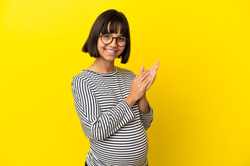 Young pregnant woman over isolated yellow background applauding