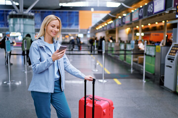 Travel and technology. Online check-in. Female traveler using smartphone waiting for boarding near registration desk line.