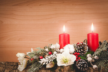 Christmas composition made with cork bark, pine, white flowers, red berries, red candles with hot flame, pine cones and snowy branches on wooden background