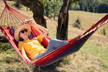 Obraz na płótnie Canvas Young woman resting in hammock outdoors on sunny day