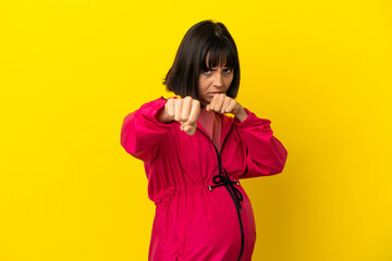 Young pregnant woman over isolated yellow background with fighting gesture
