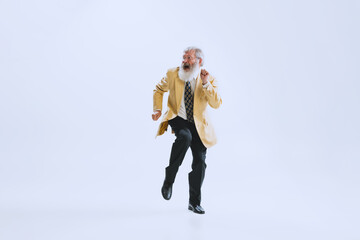 Portrait of emotional senior man in retro style clothes, vintage outfit dancing rock-and-roll isolated on white background