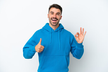 Fototapeta premium Young caucasian man isolated on white background showing ok sign and thumb up gesture