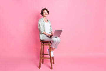 Full size photo of business bob hairdo young lady sit laptop look empty space wear grey green look isolated on pink background
