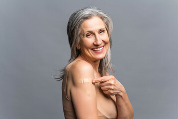 Mature gray-haired woman protect herself with vaccine against covid and other viral disease, happy...