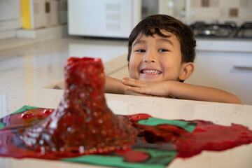 Happy cute boy experimenting with volcano eruption