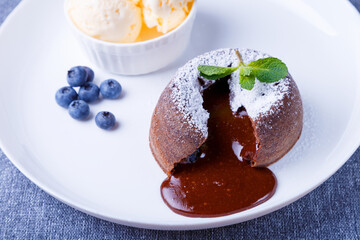 Lava cake with dripping filling. Chocolate fondant cake with vanilla ice cream, blueberries and mint. Traditional French pastries. Close-up.