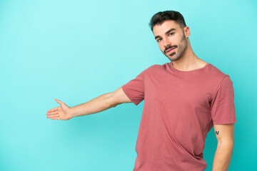 Young caucasian man isolated on blue background extending hands to the side for inviting to come