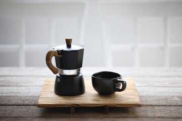 Black coffee cup and black moka pot on wooden table