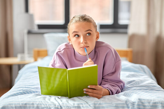 education, people and leisure concept - thinking girl with diary lying on bed at home