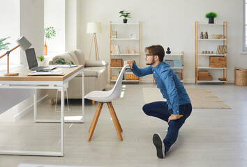 Workplace fitness. Young businessman combines work and healthy lifestyle doing sports in his home...